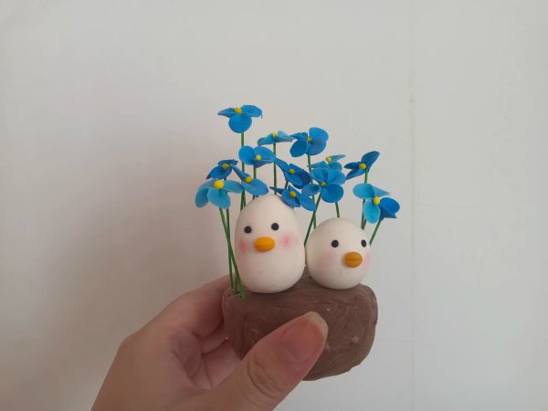 Two Adorable Clay Ducks Surrounded by Blue Flowers